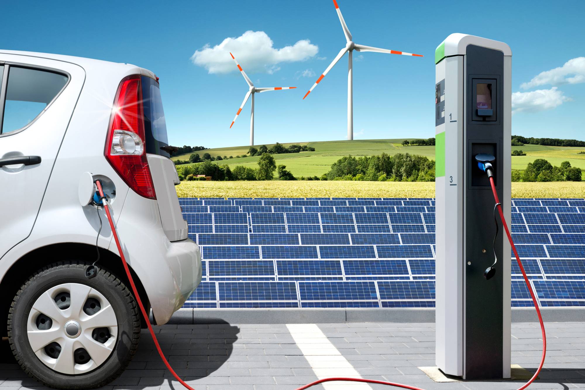 Electric car on charging spot with solar panels and wind energy in front of landscape